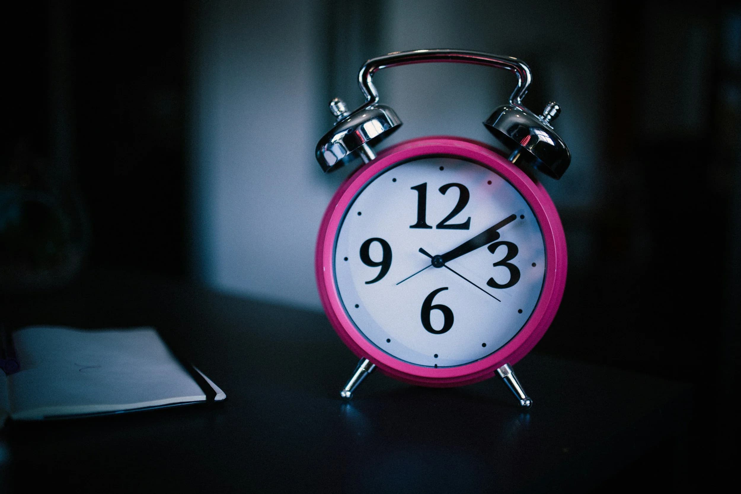 a bright pink old-fashioned analogue alarm clock