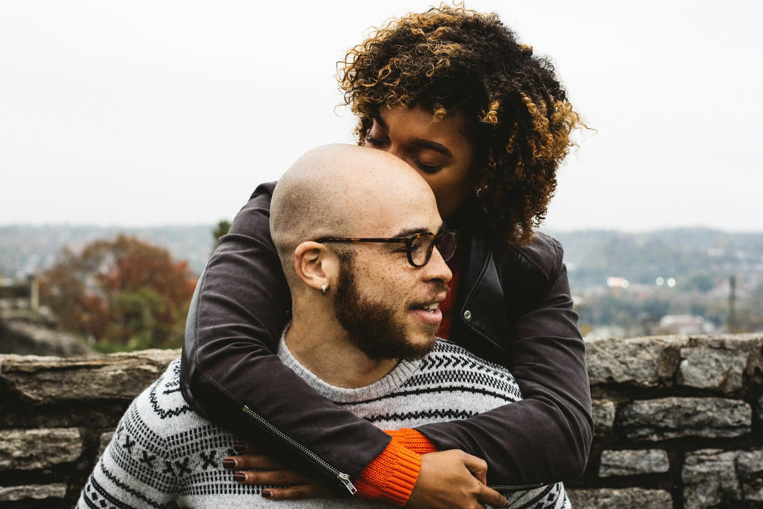a mixed heritage couple hugging with scenery in the background