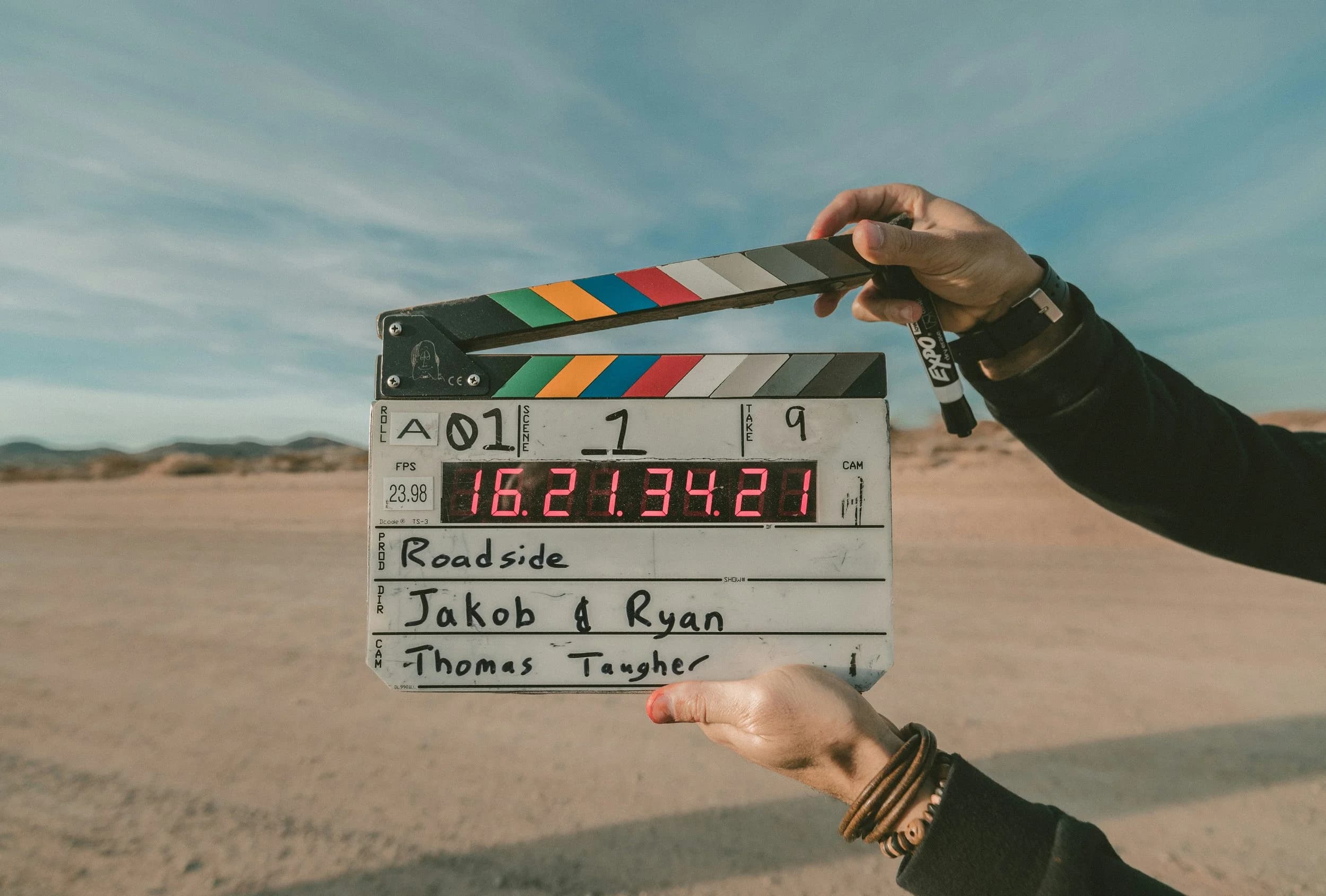A clapperboard being held up against a sunny background