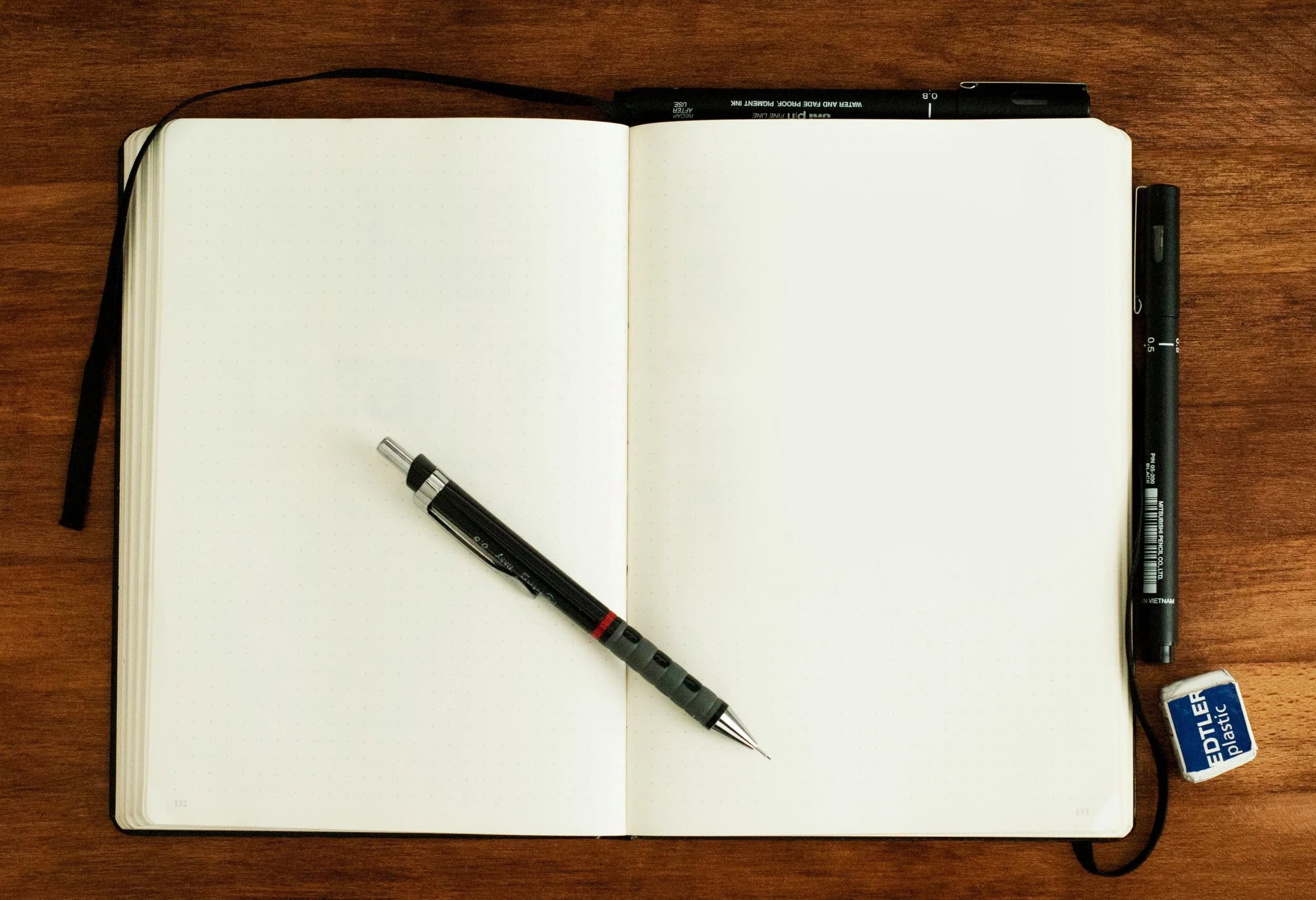 An image of a pen and a blank notebook